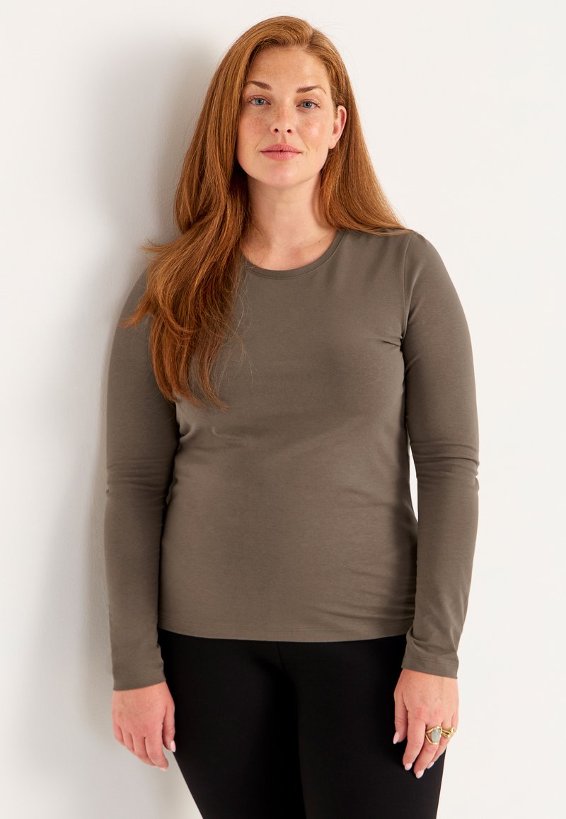 Lange mouwen, ronde hals T-shirt in olijfgroen, gemaakt van zachte, rekbare stof. Beschikt over een getailleerde silhoutte en een soepele textuur.