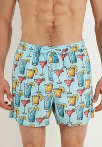 Un short de bain bleu avec un imprimé vibrant de divers cocktails, y compris des margaritas et des mojitos, avec des accents jaunes et rouges.