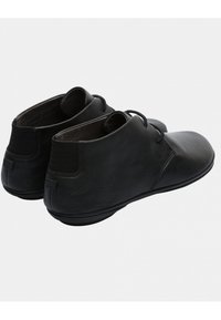 Scarpe in pelle nera con punta arrotondata, design a caviglia bassa e chiusura con lacci. Texture morbida con accenti minimalisti e suola flessibile.
