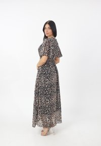 Sukienka maxi w print w panterkę z transparentnego, lekkiego materiału. Posiada krótkie falbaniaste rękawy oraz elastyczny pas. Noszona z przezroczystymi sandałami na obcasie.