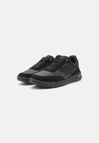 Sneakers neri con un mix di materiali scamosciati e sintetici, punta arrotondata, dettagli testurizzati e un logo colorato discreto sul lato.