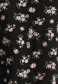 Musta kukkakuvioinen paita, jossa on valkoisia ja vaaleanpunaisia kukkia, tekstuuroitu kangas ja pienet pyöreät napit.