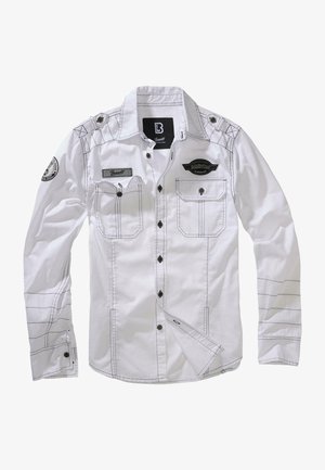 Camicia bianca a maniche lunghe con cuciture nere, due tasche sul petto e una toppa su una manica. Presenta una chiusura con bottoni sul davanti e colletto.
