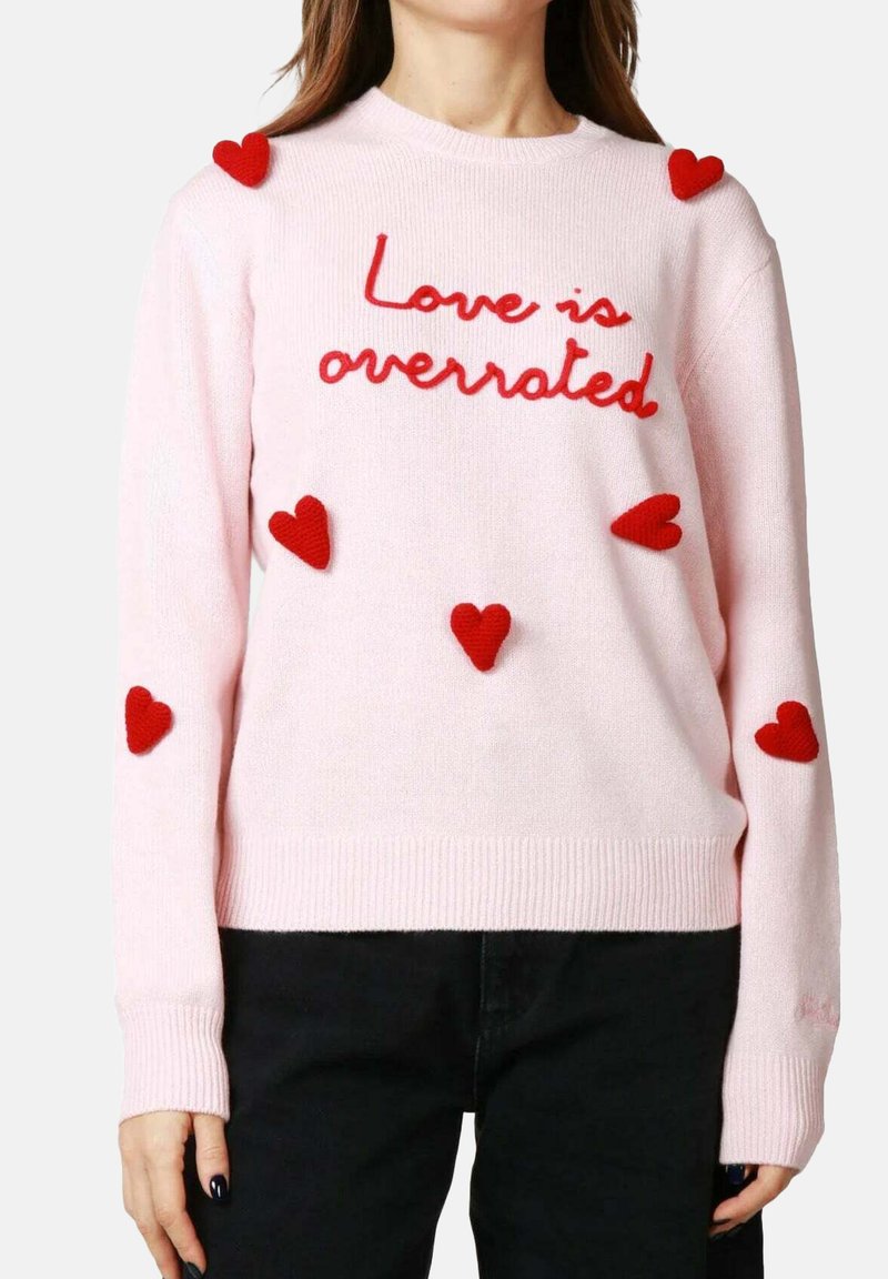 Maglione rosa lavorato a maglia con testo ricamato rosso "Love is overrated" e sei applicazioni a forma di cuore rosse sulle maniche e sul petto.