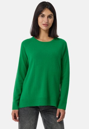 Groene gebreide trui met een ronde halslijn, geribbelde boorden en onderrand. Zachte textuur en casual pasvorm, gecombineerd met donkergrijze jeans.