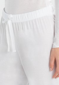 Witte loungebroek van een zachte, lichte stof. Voorzien van een elastische tailleband met een trekkoord en een gladde, onbewerkte afwerking.