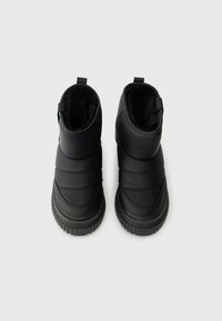 Černé zateplené boty s hladkým syntetickým povrchem, prošívaným designem, zaoblenými špičkami, texturovanými gumovými podrážkami a poutky na zadní straně.