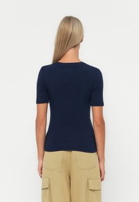 Marinblå nära passande t-shirt med korta ärmar, rund halsringning, tillverkad av mjukt, stretchtåligt tyg; slät textur och enkel design.