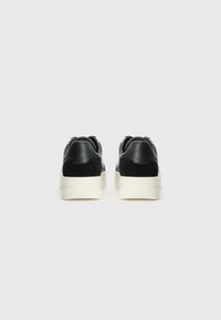 Sorte læder og ruskind sneakers med en tyk hvid sål, der har en glat overflade og rund form. Minimalistisk design, ingen synlige dele.