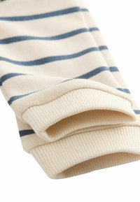 Világos bézs szövet kék átlós csíkokkal, bordás mandzsetta szegéllyel a további textúra és részletek érdekében. Puha pamut anyag.