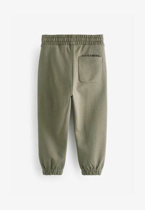 Pantaloni da tuta verdi con vita elasticizzata, polsini affusolati e una tasca posteriore con logo cucito. Texture liscia, design casual.