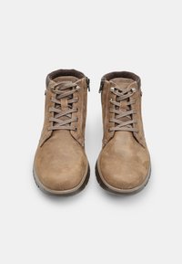 Barna bőr csizmák fűzős és oldalsó cipzáras kivitelben, matt felülettel, lekerekített orral és megerősített varrással. Gumitalp a tapadás érdekében.