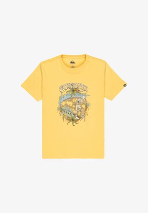 Camiseta de algodón amarilla con un estampado gráfico de un esqueleto surfeando entre plantas y olas. Diseño de mangas cortas y cuello redondo.