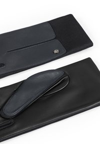 Gants en cuir et en tissu en noir et bleu marine. Paume et accents en cuir lisse, tricot texturé au niveau du poignet, avec un détail de bouton.