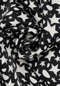 Zwart-witte stof met een patroon van sterren en abstracte vormen. Gladde textuur met een lichte glans, ideaal voor diverse textieltoepassingen.