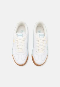 White sneakers with textured leather, light blue accents, and beige rubber soles. Features standard lace-up design and logo on tongue.