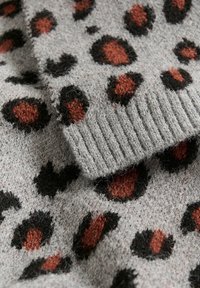 Tessuto a maglia grigia con stampa leopardata, caratterizzato da macchie nere e color ruggine. Il tessuto ha una texture morbida e bordi ribattuti.