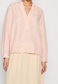 Lichtroze linnen blouse met lange mouwen, V-hals en een relaxed fit; heeft een subtiele textuur en een rechte zoom.