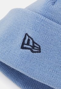 Ανοιχτό μπλε πλεκτό σκουφάκι με διπλωμένο γείσο. Διαθέτει αντίθετο μαύρο κεντημένο λογότυπο στο πλάι. Μαλακό, υφασματοποιημένο υλικό.