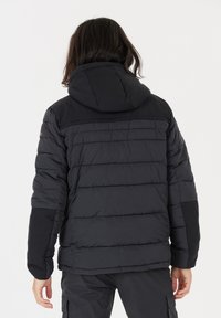 Sort puffjakke med snoretræk i hætten, med en quiltet design, ribbede detaljer og sidelukninger i kontrasterende tekstur.