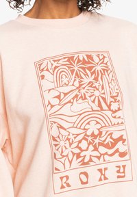 Fersken sweatshirt med en korall grafisk design som inkluderer tropiske elementer, regnbue og surfemotiver; ribbestrikket krage og avslappet passform.