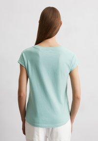 Lichtblauwe t-shirt met korte opgerolde mouwen, een zachte textuur, ronde halslijn en een relaxte pasvorm, van de achterkant weergegeven tegen een neutrale achtergrond.