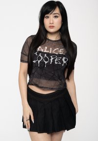 Black sheer t-shirt with "ALICE COOPER" graphic in white, paired with a black pleated skirt. Smooth texture, cropped design, and visible stitching.