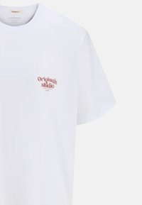 White cotton T-shirt with short sleeves and a crew neck. Features a small red "Originals studio" print on the left chest area.