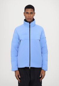 Light blue puffer jacket with a high collar, front zipper, and black accents. Features a smooth texture and quilted pattern.
