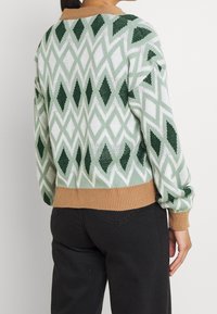 Sweter dziany z zielono-białym wzorem w diamenty, z beżowym prążkowanym dołem i mankietami. Wykonany z teksturowanej przędzy dla przytulnego dopasowania.