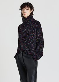 Maglione nero a maglia grossa con riflessi multicolori. Collo alto e vestibilità ampia, abbinato a pantaloni in pelle nera; tessuto testurizzato.