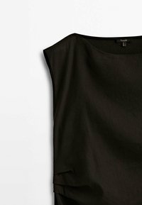 Blouse noire sans manches avec un col rond et une coupe décontractée, présentée sur un fond blanc uni.