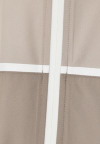 Beige tyg med en subtil textur, som har två horisontella vita ränder och en central dragkedja. Sömnadsdetaljer längs kanterna.