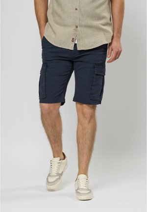 Navy cargo shorts in a lightweight fabric, featuring two side pockets and two larger flap pockets; paired with a light button-up shirt and sneakers.