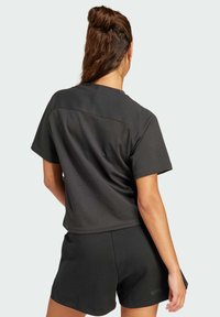 Top negro de manga corta con un corte relajado y un panel texturizado en la parte posterior, combinado con pantalones cortos negros a juego, todo hecho de una tela ligera.