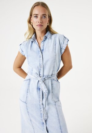 Robe chemise en denim clair à manches courtes, avec boutons sur le devant et ceinture à nouer. Dispose de poches latérales et d'une coupe décontractée avec des coutures visibles.