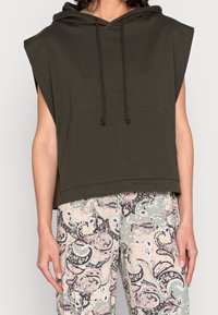 Bezrukávý tmavě zelený kapucňák s tkaničkami, doplněný o kalhoty s vysokým pasem s pastelovým paisley a květinovým motivem.