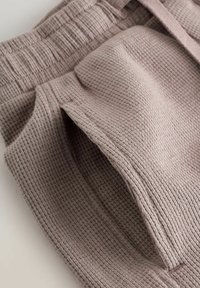 Šortky z waffle pleteniny v jemnej taupe farbe s elastickým pásom a bočnými vreckami, s textúrovaným, mäkkým vzhľadom.