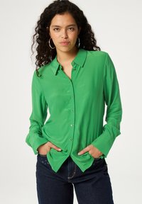 Groene button-up shirt met een kraag, lange mouwen en hartvormige gouden knopen. Glad textuur en normale pasvorm. Draag het met donkere jeans.