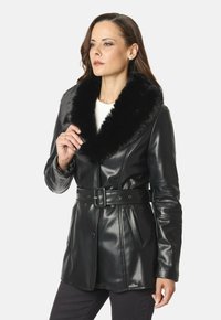 Chaqueta de cuero negra con un suave cuello de piel de fur negro, cierre de botones, cintura con cinturón y bolsillos laterales. Textura suave con un corte ajustado.