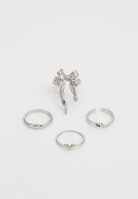 Conjunto de anillos de plata con un diseño en forma de lazo, tres bandas lisas, una de ellas con un detalle de corazón y varias formas de anillo, todo con acabado pulido.