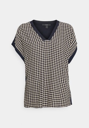 Korte mouwen V-hals blouse met marineblauw en beige polkadot patroon en effen marineblauwe afwerking aan de mouwen en halslijn.