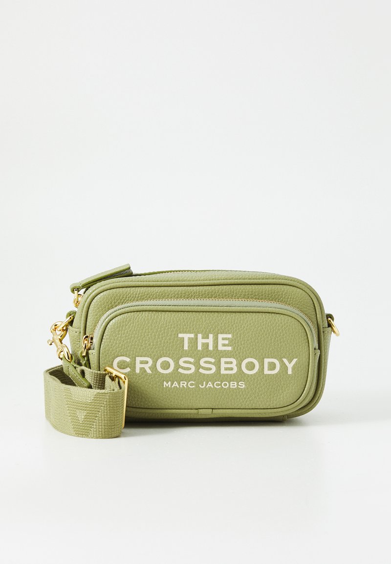 Oliivivihreä nahkainen olkalaukku, jossa on kultaiset vetoketjut ja säädettävä hihna. Etupuolella teksti "THE CROSSBODY MARC JACOBS."