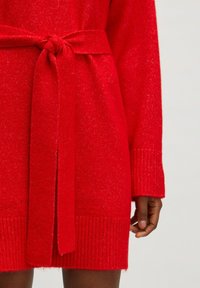 Rotes gestricktes Kleid mit einem Gürtel, das eine strukturierte Optik, gerippte Bündchen und eine lässige Passform aufweist. Der Stoff hat einen dezenten Schimmer.