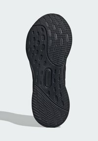Semelle de chaussure en caoutchouc noir présentant un motif texturé avec des formes hexagonales et ovales, offrant adhérence et traction.