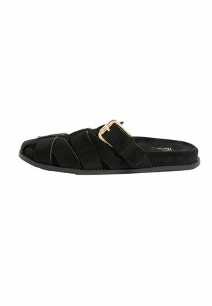 Schwarze flache Slide-Sandale mit überkreuzten Wildlederriemen und einer goldenen Schnalle auf weißem Hintergrund.