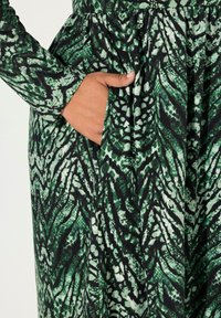 Pitkähihaisen mekon vihreä ja musta kuvio, jossa on kootut vyötärö ja piilotettu sivutasku. Valmistettu pehmeästä, verkkot tekstuurista kankaasta.