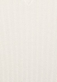 Weißer Strickpullover mit vertikaler Rippstruktur und V-Ausschnitt. Weiches Material mit gleichmäßiger Nahtführung und ohne sichtbare Verzierungen.