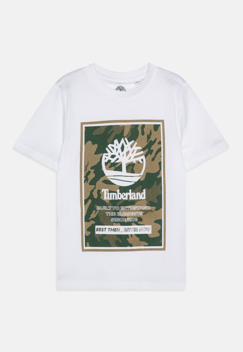 Camiseta de algodón blanca con un estampado gráfico de camuflaje en verde y marrón, que incluye un logo de árbol blanco y texto. Cuello redondo, mangas cortas.