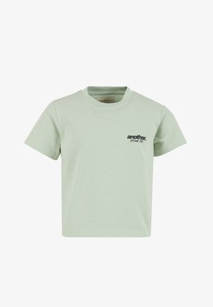 Jasnozielona bawełniana koszulka z okrągłym dekoltem i krótkimi rękawami. Z białym logo tekstowym po lewej stronie. Gładka faktura.